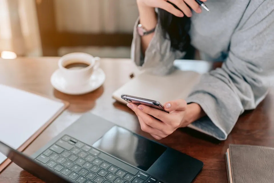 Professional woman using laptop and phone